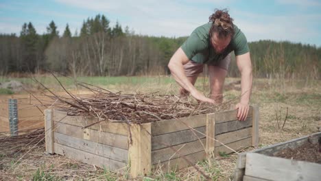 man putting twigs in wooden planter - wide