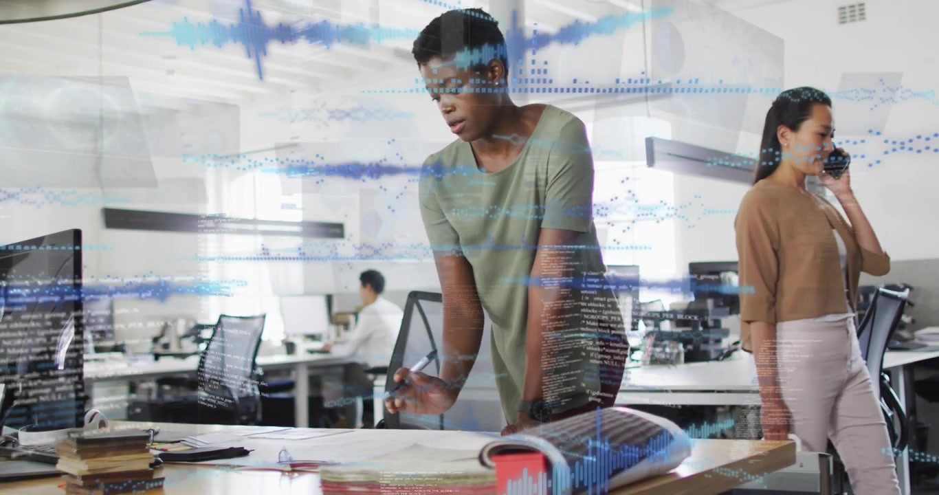 Diverse team framing African American woman in green top leaning over desk marking plans with pen