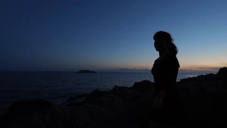 그녀의 뒤에 일몰과 함께 잔잔한 바다 옆에 젊은