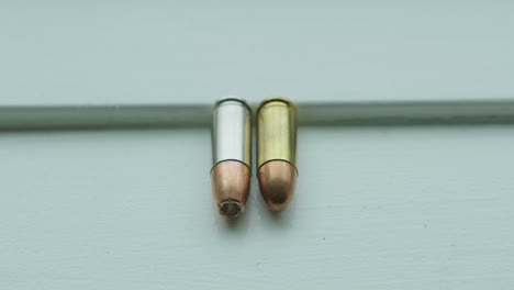 close up pan right of a hollow point and a round nose 9mm bullet side by side