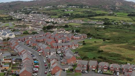 aerial view over suburban town brick house neighbourhood tilting up to holyhead mountain
