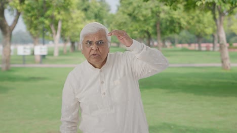 confused indian old man looking and finding someone in park