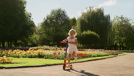 a young girl riding a scooter in a vibrant flower park