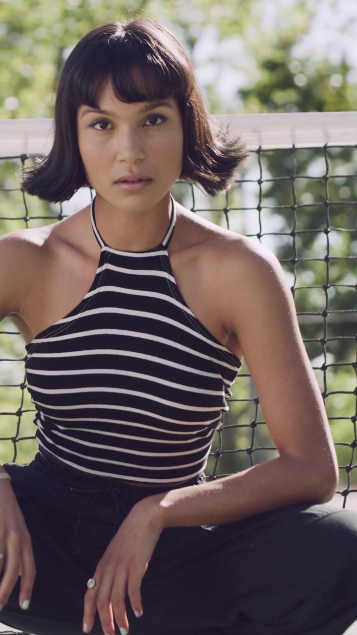 Giovane Donna in Posa vicino alla Rete di un Campo da Tennis