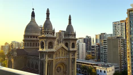 pan shot of sacramentinos church surrounded by santiago's skyscrapers at sunset, chile