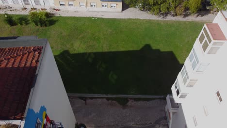 el vuelo aéreo del avión no tripulado se desliza a lo largo del costado de un edificio residencial, capturando un lienzo vibrante de pinturas de graffiti coloridas por una persona de pie en una grúa de ascensor
