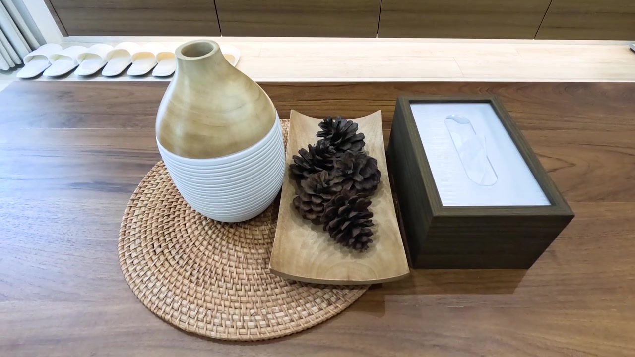 La caméra en plongée s'éloigne de pommes de pin et d'un vase en céramique sur une table en bois