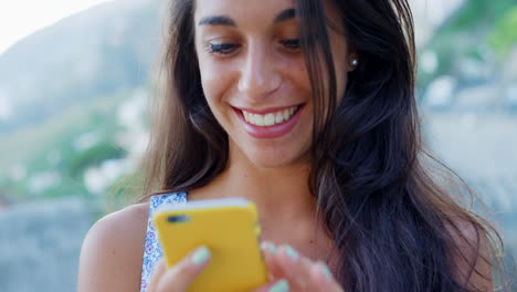 young woman smiling and looking at her phone outdoors