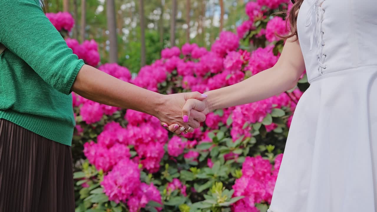 Connection across generations surrounded by bright pink rhododendron blossoms