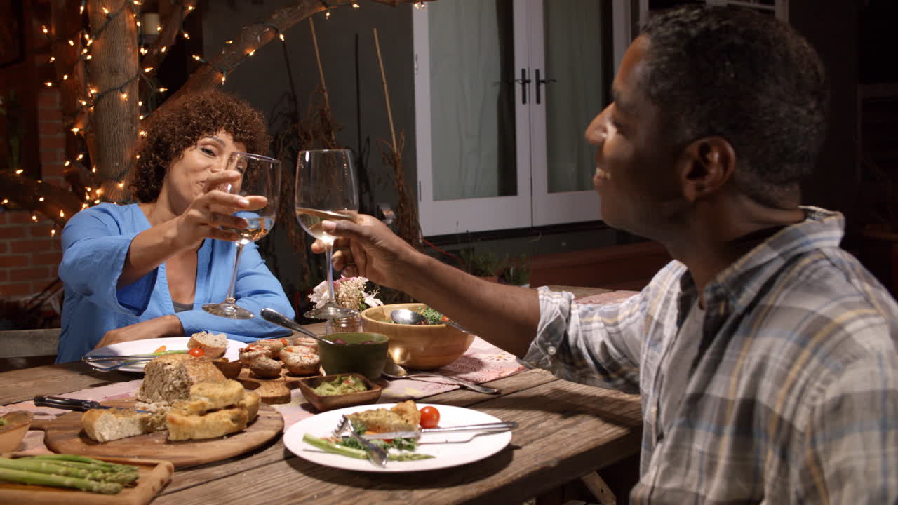 Mature Couple Enjoying Outdoor Meal In Backyard