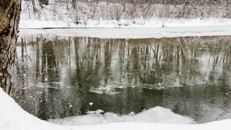 Snowflakes-falls-on-a-calm-river-in-New-England