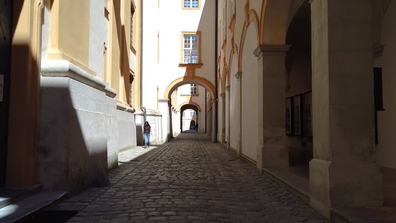 This video showcases a charming alleyway surrounded by old captivating architecture that has stood the test of time