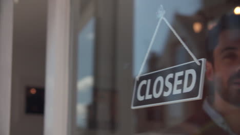 shop owner changing shop sign from closed to open