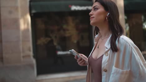 una mujer bonita caminando y sosteniendo un móvil.