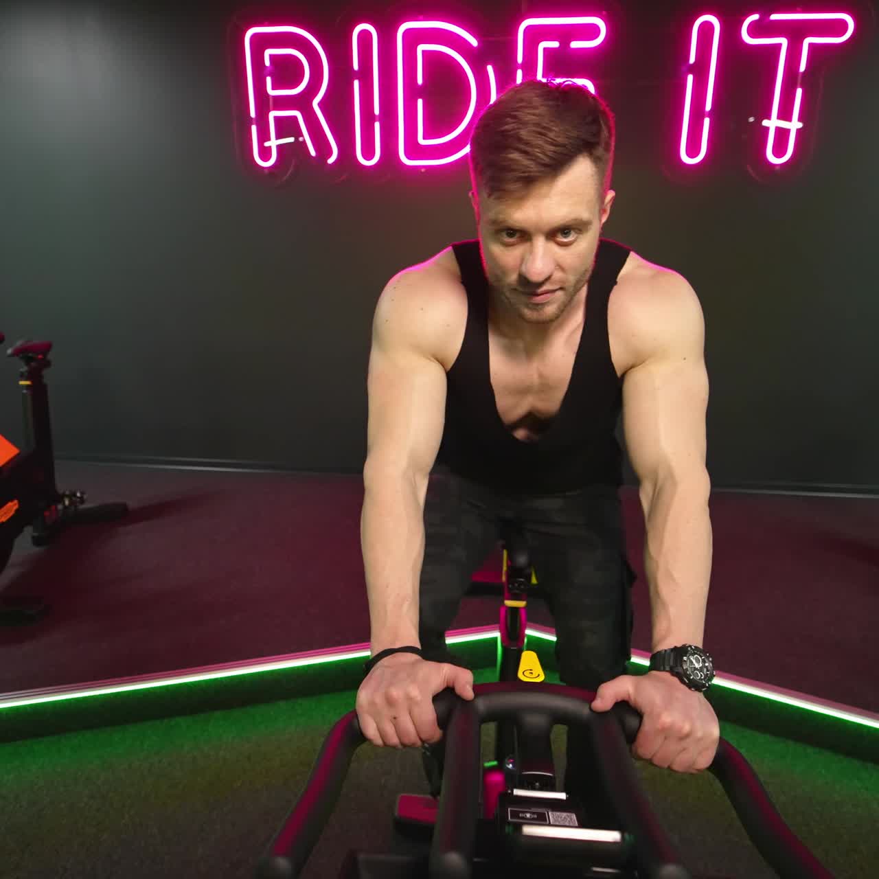 Man training on spin bike. Front view of man spin legs on smart trainer in gym