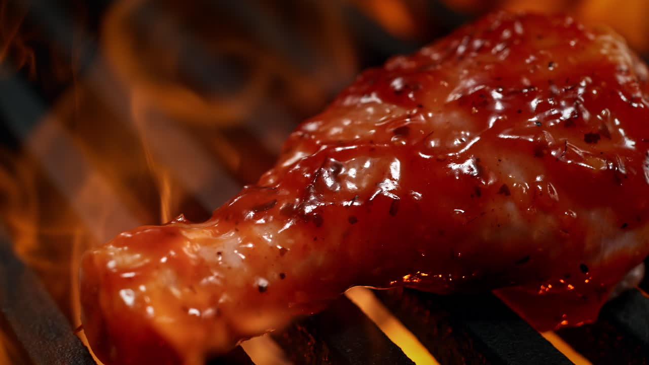 palos de tambor marinados a la parrilla en una parrilla de carbón entre las llamas del fuego en cámara lenta y macro