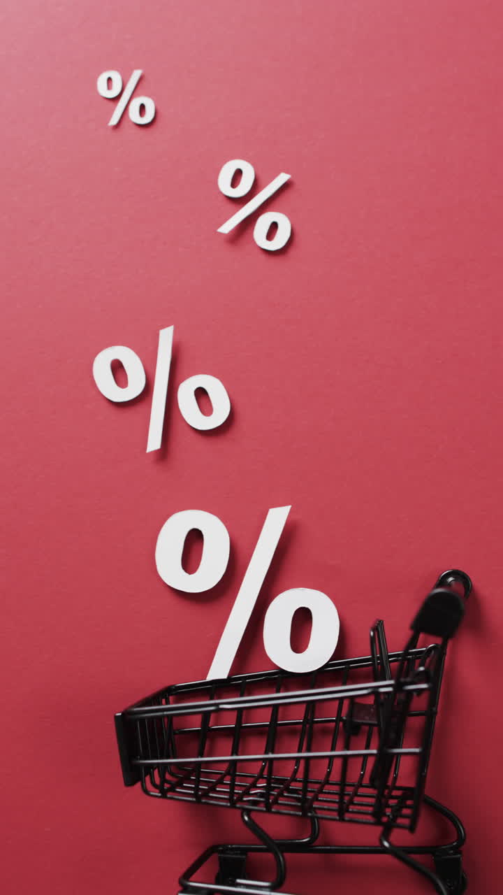 Vertical video of shopping trolley and white percent signs on red background