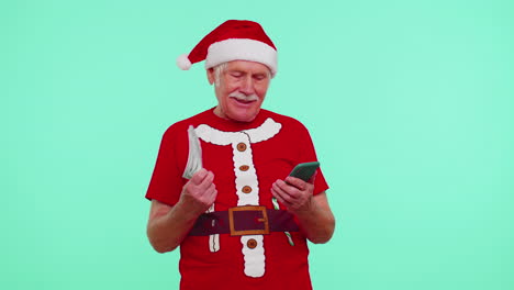 Abuelo-De-Navidad-Mirando-Teléfono-Inteligente-Regocijándose-Sinceramente-Ganar-éxito-Suerte-Recibir-Dinero-En-Línea