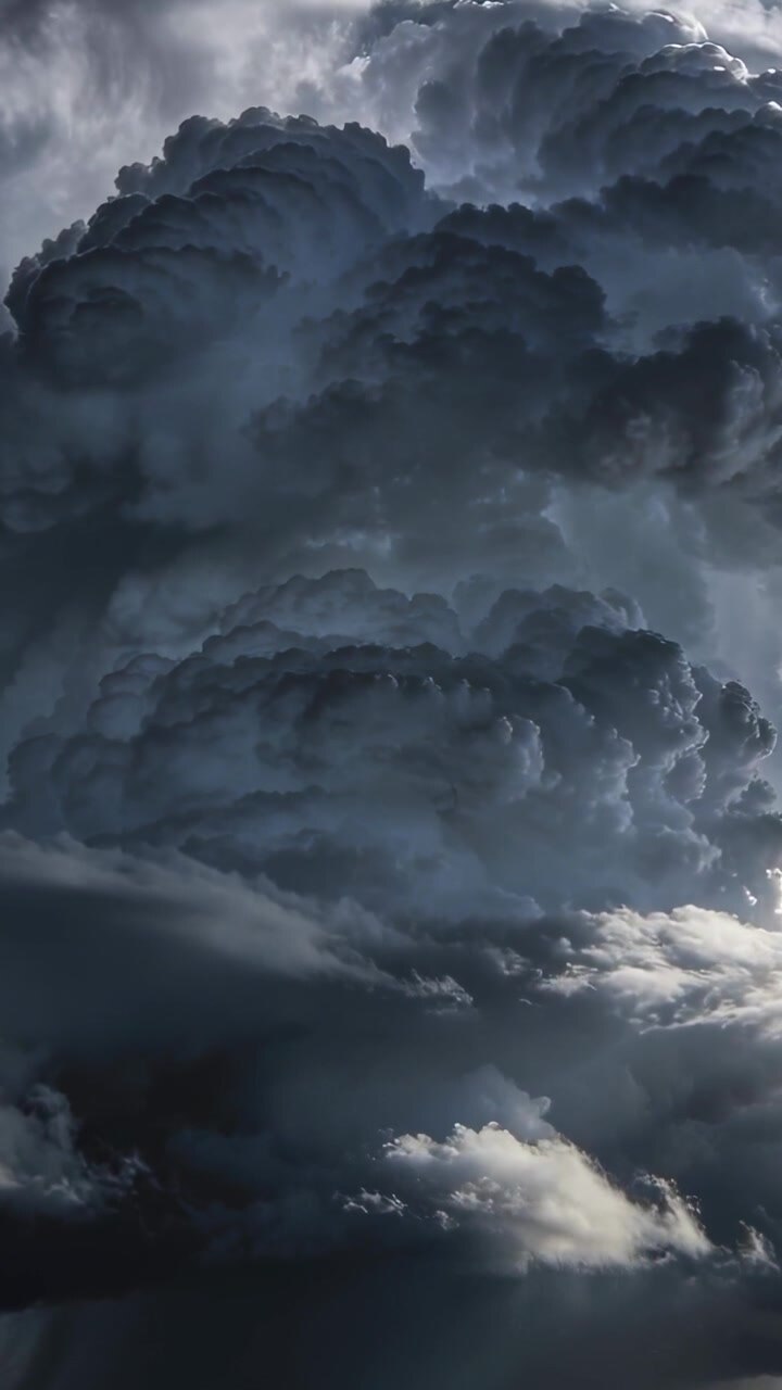 Video verticale: Cumulonembo in crescita che si innalza, mostrando raggi di sole e virga nel cielo, spinto da correnti ascensionali.