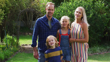 portrait of caucasian parents with son and daughter standing in garden smiling