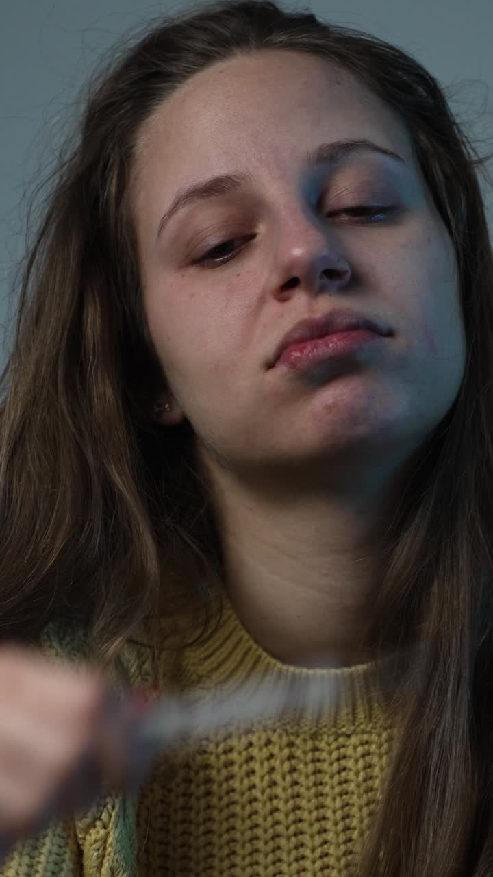 Primo piano di una donna con influenza stagionale, che si tiene la testa e controlla un termometro, mostrando sintomi di dolore e febbre a casa.
