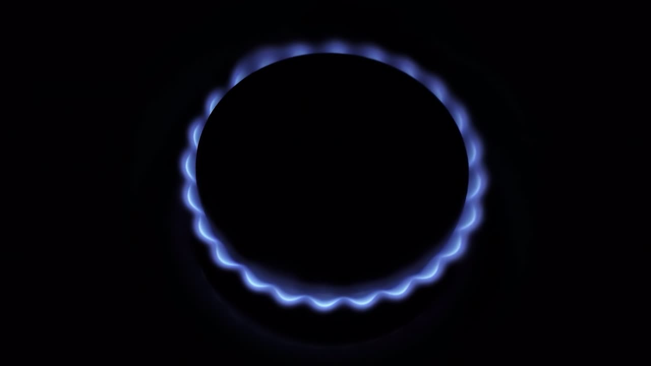 horno de estufa de gas ardiente, llamas azules macro primer plano en la oscuridad sobre un fondo negro. quemador de gas con llama que se desvanece lentamente. video en bruto 4k con movimiento suave de la cámara.