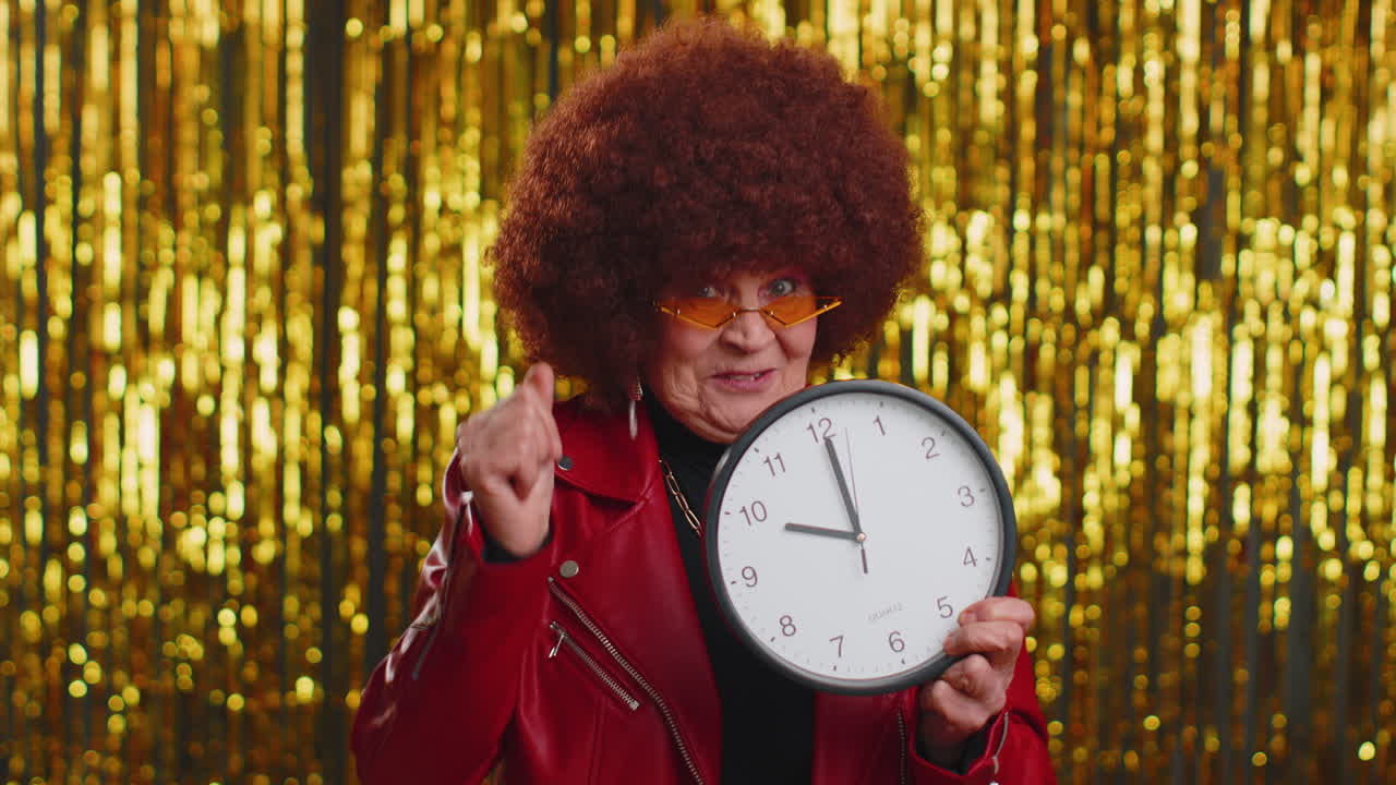 mujer mayor con estilo que muestra el tiempo en el reloj, ok, pulgar hacia arriba, aprobar, señalando con el dedo a la cámara