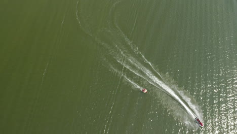 aerial top down, friends having summer fun tubing, pulled by motor boat on green lake