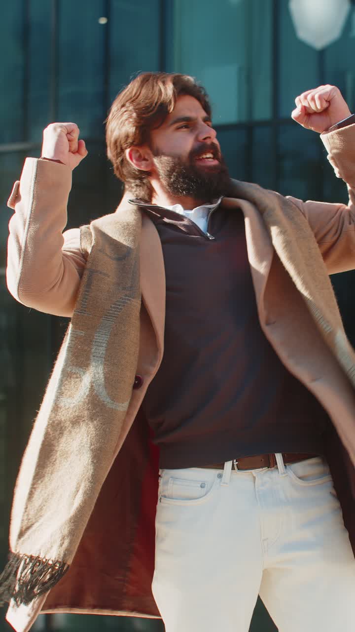 흥분한 남자가 놀라서 주먹을 고 갑작스러운 승리에 충격을 받고 도시 거리에 서 있습니다.