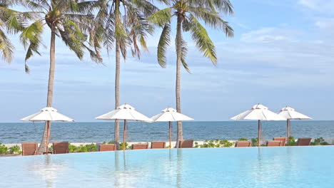 Infinity-Pool-Lounge-Mit-Aufgestellten-Liegestühlen-Und-Sonnenschirmen-Am-Strand-Am-Meer-Im-Exotischen-Ilsand-In-Thailand-An-Bewölkten-Tagen