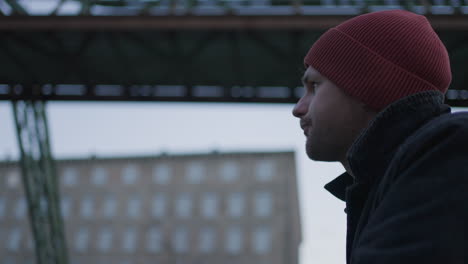 CloseUp-of-young-man-lost-in-thought-under-Wuppertal-Railway-during-winter