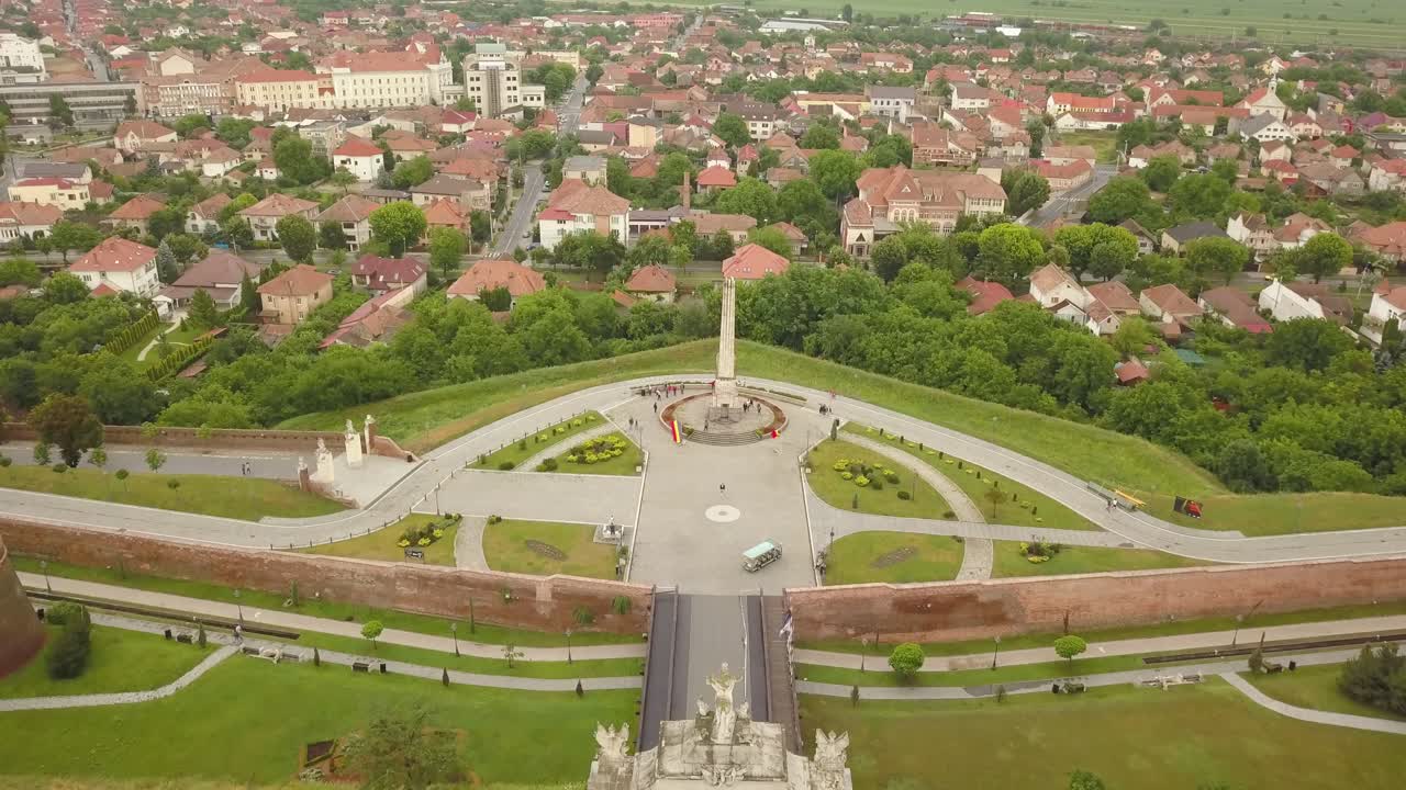 High Altitude Aerial Establishing shot of monument in Citadel Alba-Carolina, Alba-Iulia, Romania with City and greenery in shot