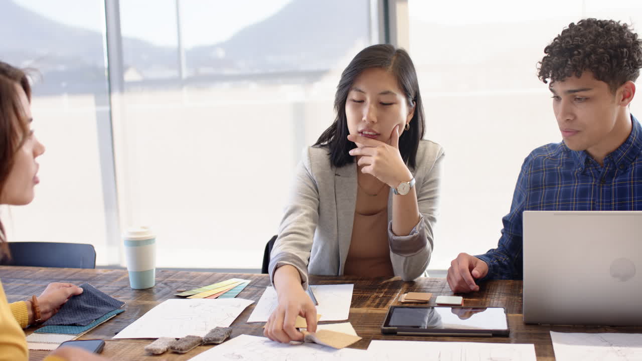 Interior design plans, multiracial team using tablet, laptop, and samples, at office