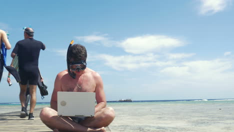 Man-in-snorkel-using-pad-on-pier