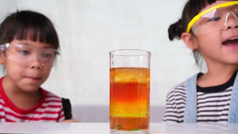 children are learning and doing science experiments in the classroom. two little sisters playing science experiment for home schooling. easy and fun science experiments for kids at home.