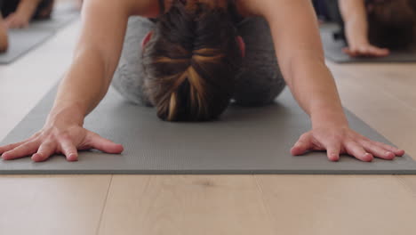 yoga class instructor teaching group of young women childs pose on exercise mat enjoying healthy lifestyle training meditation practice in fitness studio