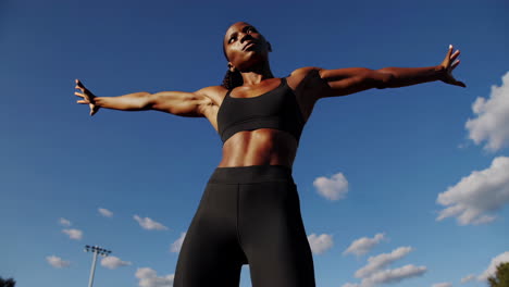 confident athletic woman posing under blue sky