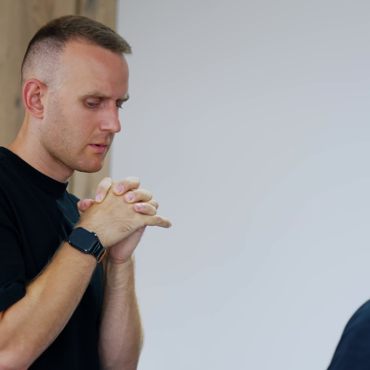 Worried Caucasian man wearing black t-shirt walks by the hospital ward. Husband is nervous while his wife giving birth to a baby