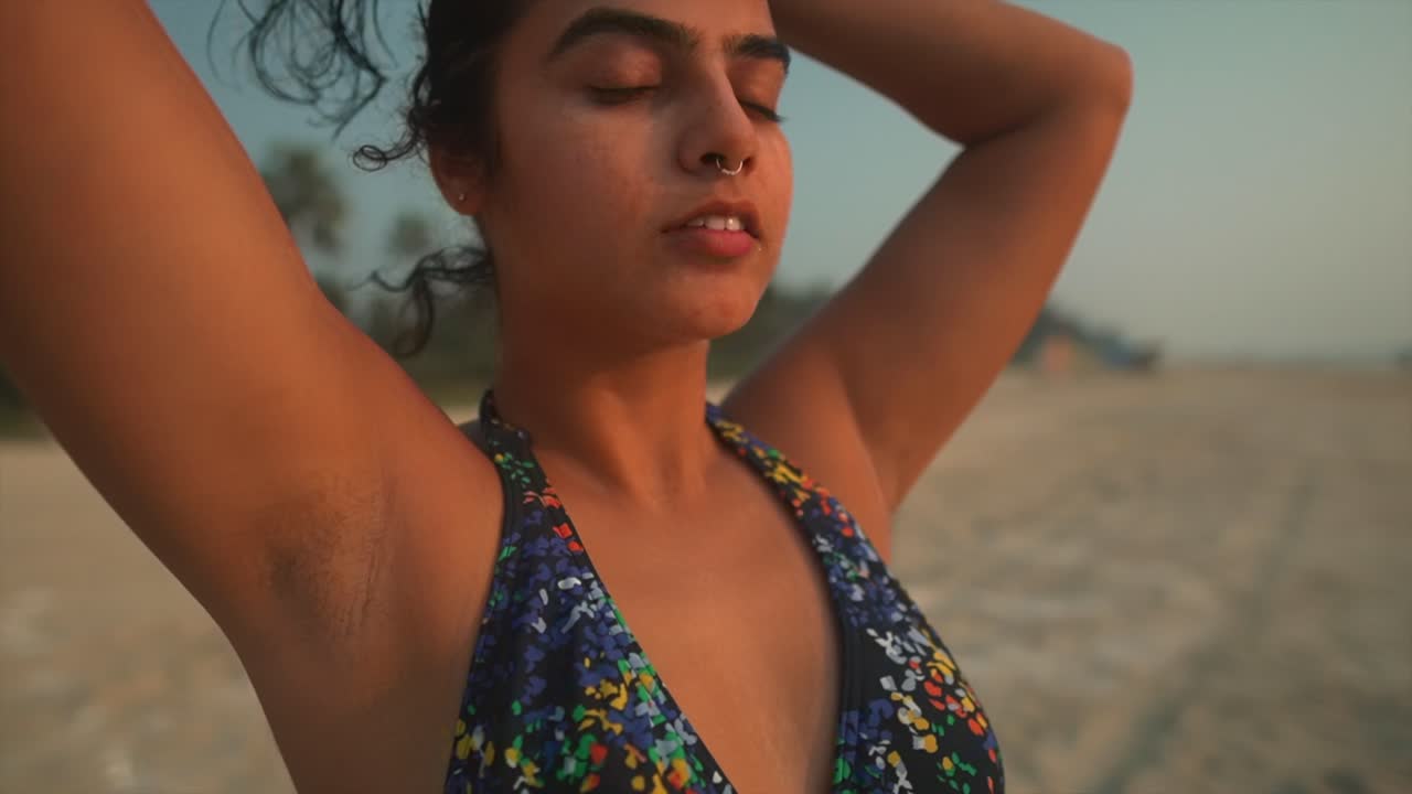 Ragazza che si sistema i capelli ricci e bagnati sulla spiaggia.