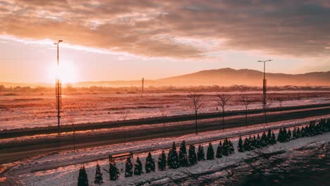 sunrise behind a snowy mountain with an open road inside, drone 4k