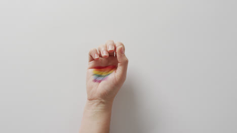 video of hand of caucasian man with rainbow flag on white background