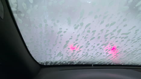 close up shot of automatic machine sprays water to clean the soap of the windshield