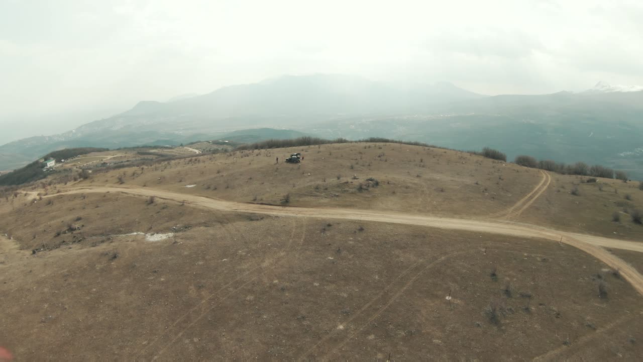 paisaje montañoso con caminos de tierra y vehículo