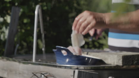 Tiro-Medio-De-Manos-Adultas-Masculinas-Lavando-Pescado-En-Rodajas-Al-Aire-Libre-En-El-Patio-Trasero,-Enfoque