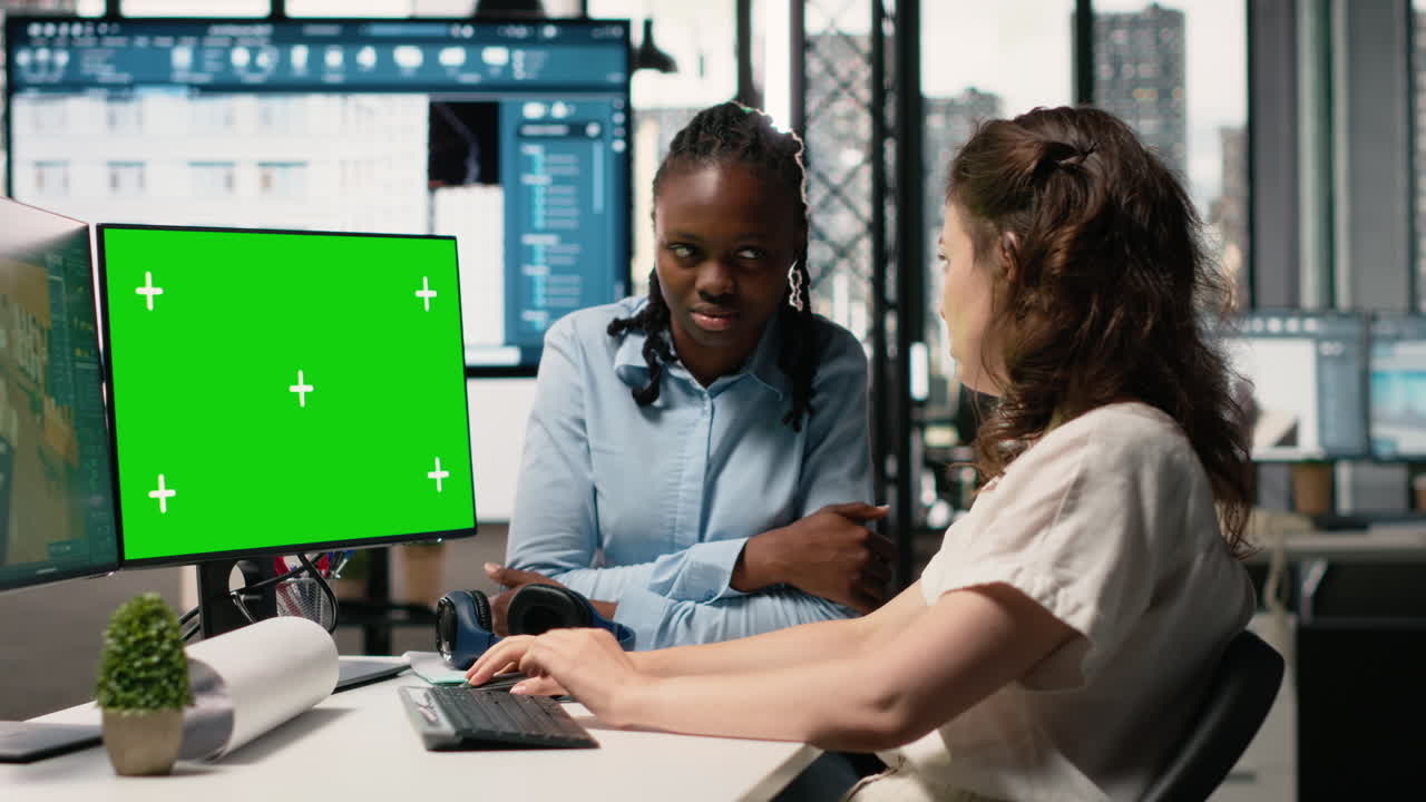 Two Women Working Together on a Green Screen Computer in an Office