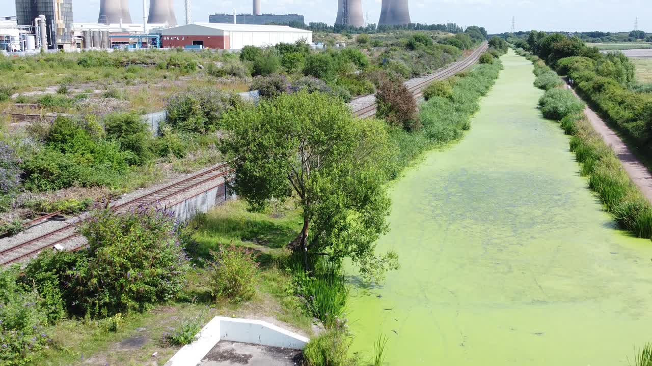 canal cubierto de algas verdes vía fluvial que conduce a la industria de la central eléctrica vista aérea drone inclinar hacia adelante lento hacia arriba
