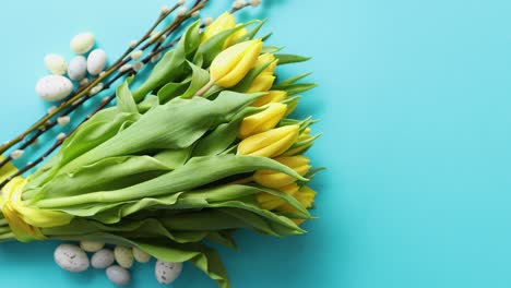 holiday contept decoration with easter eggs and yellow tulips over blue