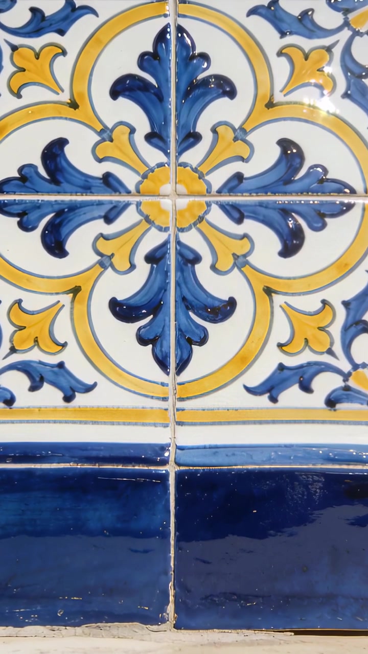 Video verticale: Telecamera in movimento che si sposta sopra un muro, rivelando una rosetta in ceramica, la stuccatura e una fascia blu.