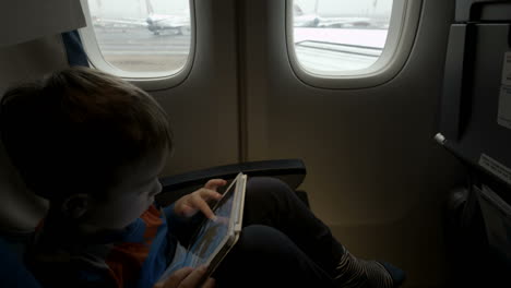 boy sitting in the plane and using tablet pc