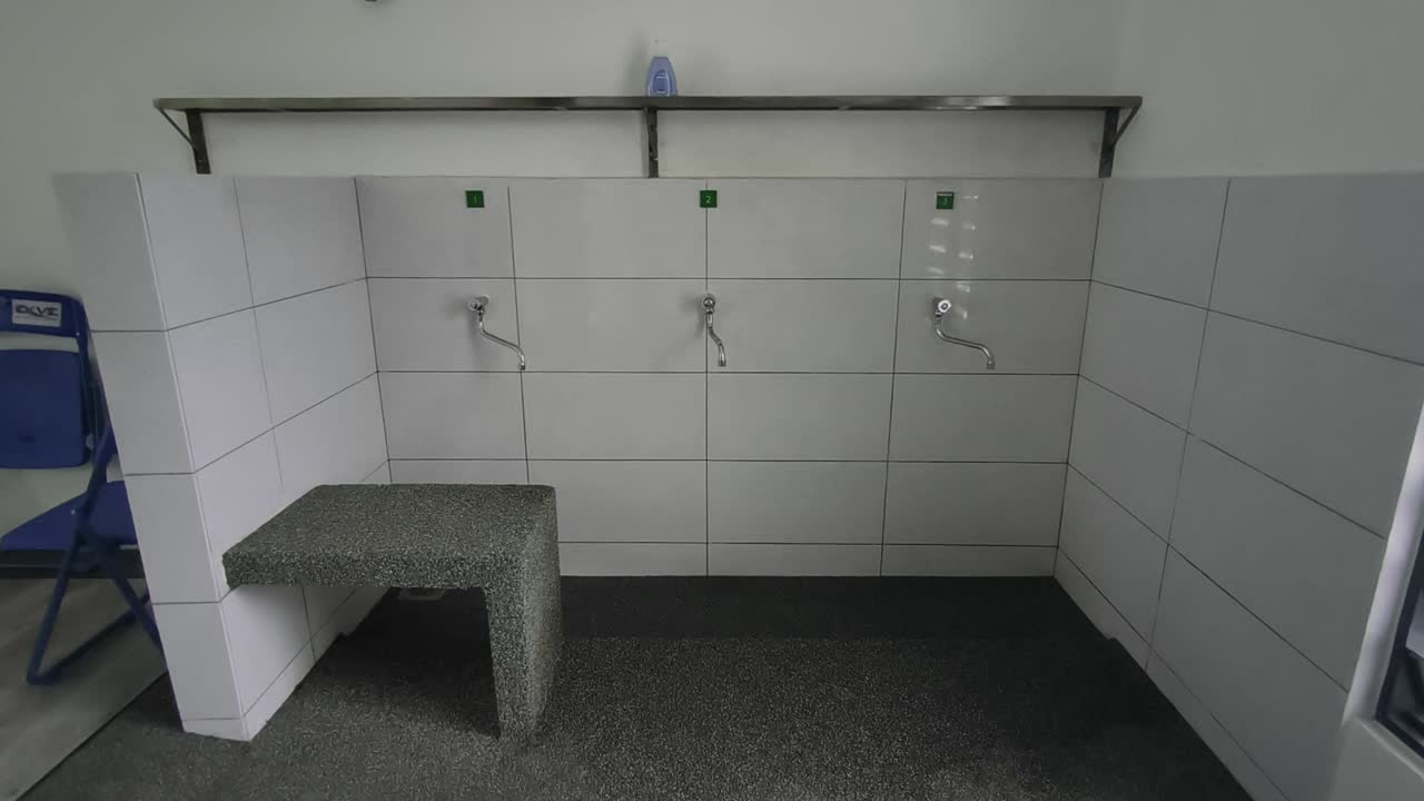 A close-up of a clean ablution area at a small Malaysian highway prayer room. Water flows for ritual washing as travelers prepare for prayer